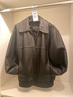 Front view of the black Beardmore leather jacket hanging on a rod, showing full front with zipper closed.
