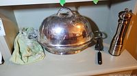Silver plate meat tray with lid, server, and pepper mill set arranged on a shelf