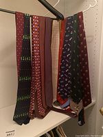 Group photo showing nine men's neckties in various patterns and colors hanging on a black hanger.