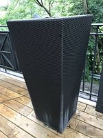 Front angled view showing the tall rectangular shape and woven wicker texture of the planter placed outdoors