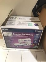 Box labeled Brother HC1850 Computerized Sewing & Quilting Machine showing product features and branding.