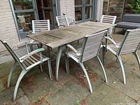 Six metal frame chairs with wood slats arranged around matching outdoor table on patio