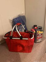 Red folding basket, blue tarpaulin in packaging, pesticide bottles and lightbulbs arranged on carpeted stairs.