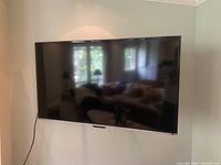 Full front view of the 58 inch Toshiba TV mounted on the wall with power cord visible hanging down.