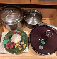 Drawer view showing two stainless steel pots with lids and purple tagine lid at right