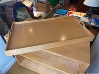 Top angled view of large wooden tray showing smooth finish and raised edge detail.