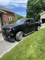 Front and driver side of black crew cab Silverado parked on driveway