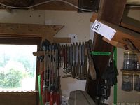 Photo showing a variety of F clamps with metal bars and red wooden handles hanging on a rack along with some other clamps.