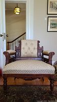Front view of vintage Eastlake style chair showing peach and gold upholstery with wood carving details.
