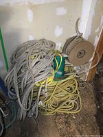 Multiple ropes coiled and bundled together on the floor, showing various sizes and colors including yellow and green ropes.