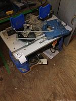 Top view of Mastercraft router table with blue fence and accessories on a wooden floor