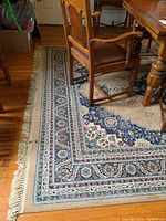 Front section of rug under a dining table showing corner fringe and border pattern