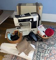 Full view of PFAFF 209 sewing machine with hard carrying case, foot pedal, sewing supplies including needles, thread, scissors, and fabric pieces surrounding it.