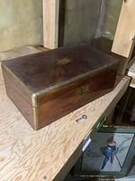 Closed view of antique wooden writing desk showing front lock with key on table
