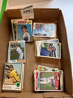 Box containing multiple stacks of vintage loose baseball cards including Nolan Ryan, Ivan Murrell, Duffy Dyer