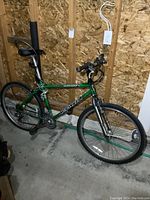 Full side view of green Kona Hahanna 21-speed mountain bike inside storage with plywood walls.