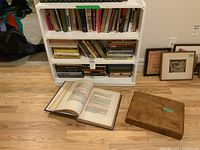 Photo showing the collection including the open Edward VII prayer book and protective wooden case on floor in front of bookshelf containing other books.