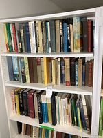 Three shelves of various sized and colored books. Hardcovers and paperbacks are included. Genres include history, literature, children's books, and military subjects.