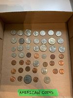 Full view of all coins arranged in a cardboard box showing different types and sizes of American coins including quarters, nickels, dimes, and pennies.