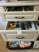 Image of a basket containing multiple folded table cloths and tea towels in various patterns and colors, resting on a lower drawer.