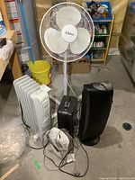 Photo showing all items in the lot: Classic pedestal fan, DeLonghi oil-filled heater, Honeywell air cleaner, and a compact heater.
