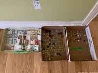 Three trays, first with assorted foreign paper money, second and third with assorted foreign coins.
