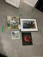 Four framed artworks on floor showing variety including watercolor, painting, and photo