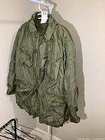 Full front of military coat hanging showing pockets and button/zip closure