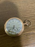 Front view of Elgin pocket watch showing white dial with Arabic numerals and detached minute hand lying on the dial.