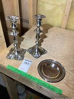 Photo showing pair of ornate Victorian silver plate candlesticks and a small round Birks silver plate dish on wooden surface.