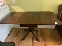 Top view of dining table with both drop leafs extended showing rectangular shape and wood grain surface.