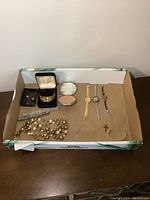 Full lot overview of vintage jewelry items arranged in box including bracelets, watches, compact, necklace, and pins