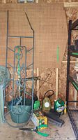 Photo showing the metal trellis, plastic bucket, watering jug, weed control products, garden stakes, and various small garden tools on a pegboard wall in a shed.