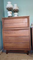 Front view of highboy dresser showing two small top drawers, three larger lower drawers, integrated recessed pulls and satin walnut finish