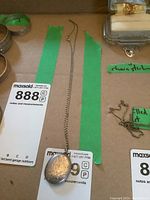 Photo showing oval sterling silver locket on 16 inch chain with floral and scroll engraving.