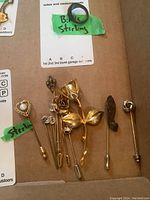 Full view of all eight pins and brooches showing a collection of floral, heart-shaped, and diamond-like accent pins, including sterling-marked items.
