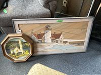 Full view of both framed art wood panel and octagonal framed Coalport plate on floor near sofa