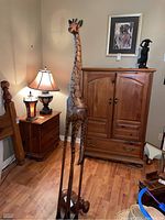 Full view of the 68-inch carved wooden giraffe standing on the floor with nearby furniture.