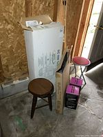 Photo of unopened large box for wooden double Muskoka chair kit, long narrow box, two wooden stools including a red cushioned top stool.