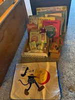 Overview of lot showing boxed puzzle map, assortment of books, boxed miniature doll furniture set, small dolls, and Mickey Mouse pillowcase