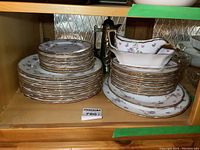 Full view of stacked china plates and serving dishes, showing the floral and gold trim pattern.