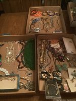 Overview of the three boxes containing assorted costume jewelry including beads, necklaces, bracelets, earrings, and brooches.