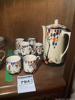 Full view of six cups, six saucers, chocolate pot and cream pitcher.