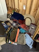 Photo showing lot with cowboy hat, shirts, purses, slippers, scarves, and board game.