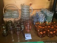 Full view of glassware collection including tumblers in basket, pitcher, and amber leaf glasses.