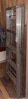 Photo of folded metal painter's ladder leaning against wood-paneled wall, showing side and step details.
