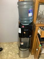 Full view of the water cooler with a large water jug on top, showing overall height and build.