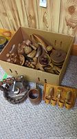 Box filled with assorted wooden items including shakers, bowls, and containers with nutcracker set beside the box