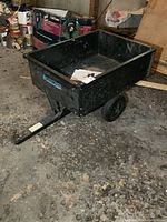 Full view of the black metal yard trailer showing cargo box and wheels.