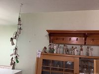 Shelf with multiple Willow Tree carved angel figurines and a hanging string ornament with small angels